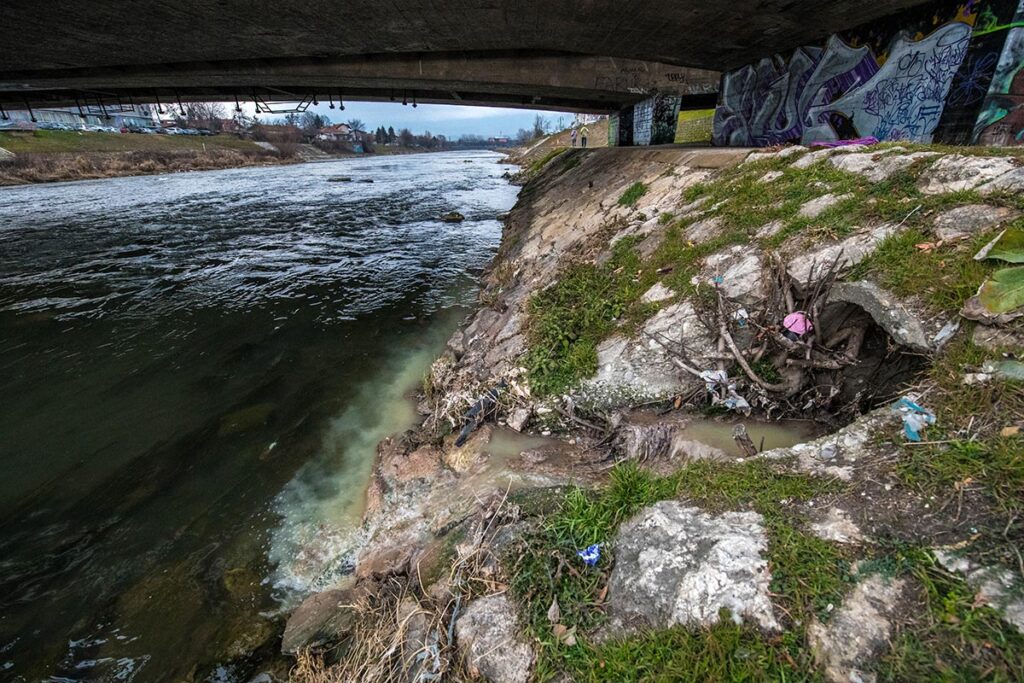 Фотографија од насобрано ѓубре околу отвор кој испушта вода на кејот во реката Вардар.